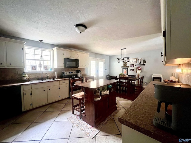 kitchen with a kitchen bar, sink, tasteful backsplash, a center island, and black appliances