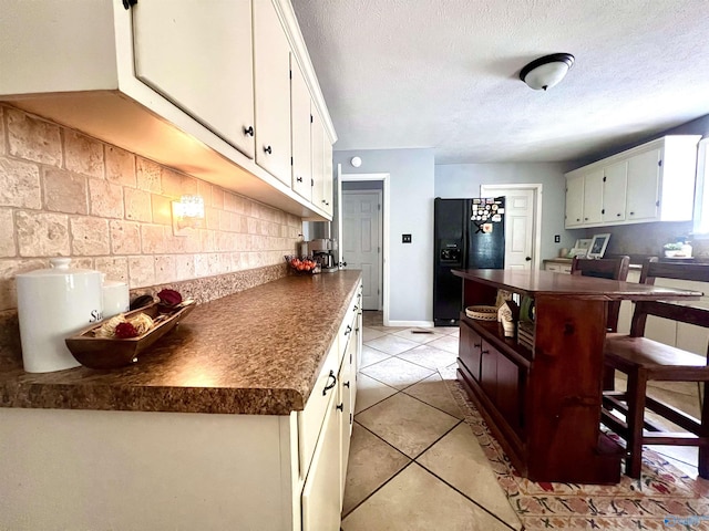 kitchen with light tile patterned flooring, white cabinets, backsplash, a textured ceiling, and black refrigerator with ice dispenser