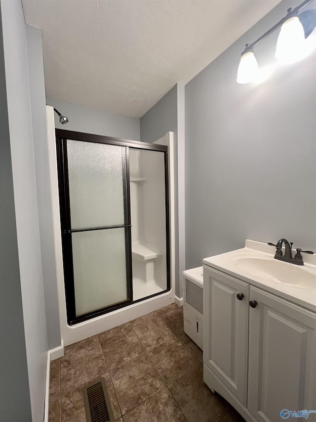 bathroom featuring vanity, a shower with shower door, and a textured ceiling