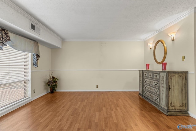 empty room with crown molding, a textured ceiling, and light wood-type flooring