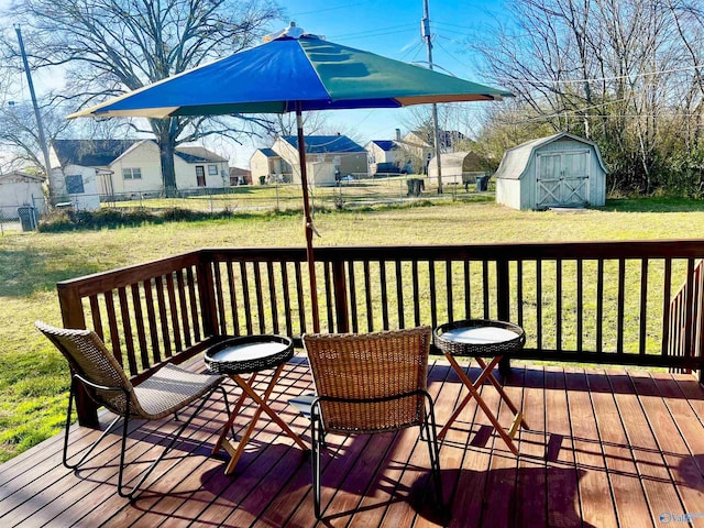 deck with an outdoor structure, a lawn, a storage shed, and fence