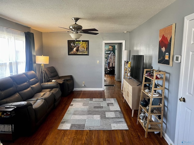 living room with dark wood finished floors, a textured ceiling, baseboards, and ceiling fan