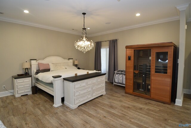 bedroom with light hardwood / wood-style floors, a notable chandelier, a fireplace, and crown molding