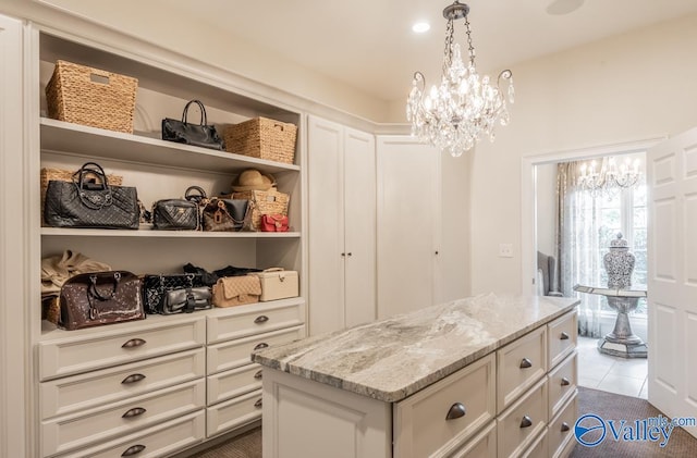 walk in closet featuring dark tile patterned flooring and a notable chandelier