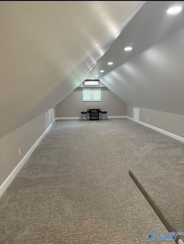 additional living space featuring vaulted ceiling, a wall mounted AC, and carpet flooring