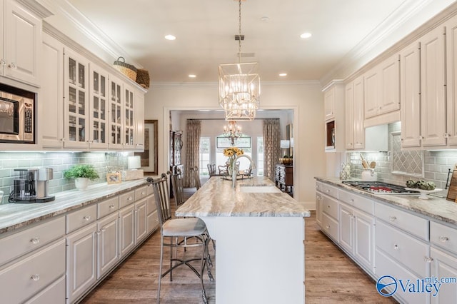 kitchen with a kitchen island with sink, backsplash, light hardwood / wood-style floors, and appliances with stainless steel finishes