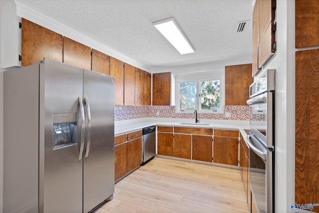 kitchen featuring a sink, visible vents, appliances with stainless steel finishes, and brown cabinetry