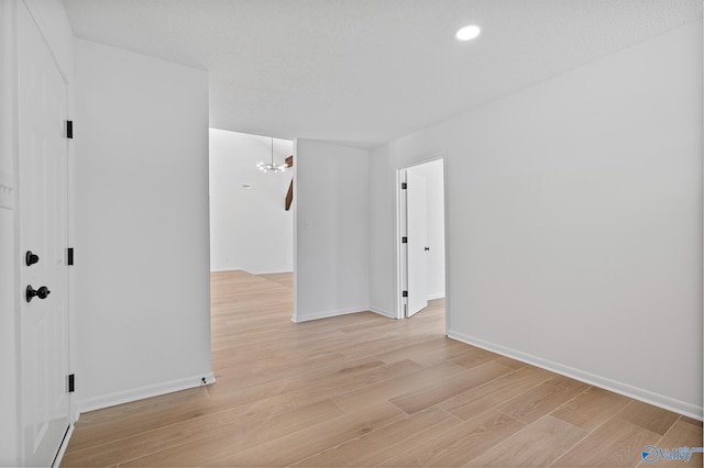 empty room featuring recessed lighting, baseboards, and light wood-style flooring