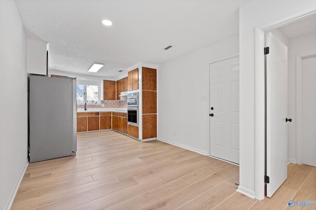 kitchen with visible vents, appliances with stainless steel finishes, light wood-style flooring, and brown cabinetry