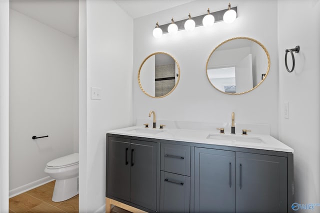 bathroom with double vanity, toilet, wood finished floors, and a sink