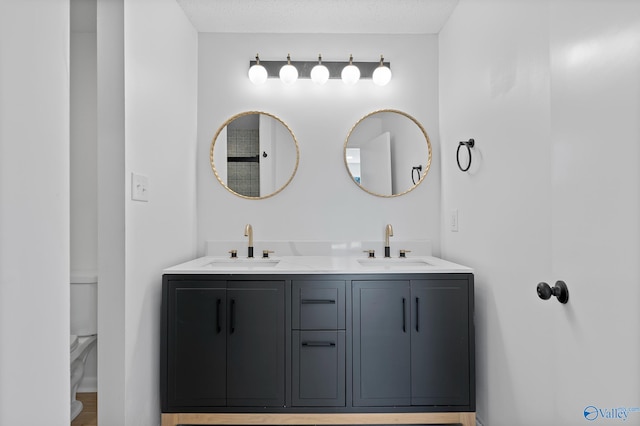 full bathroom with double vanity, toilet, and a sink