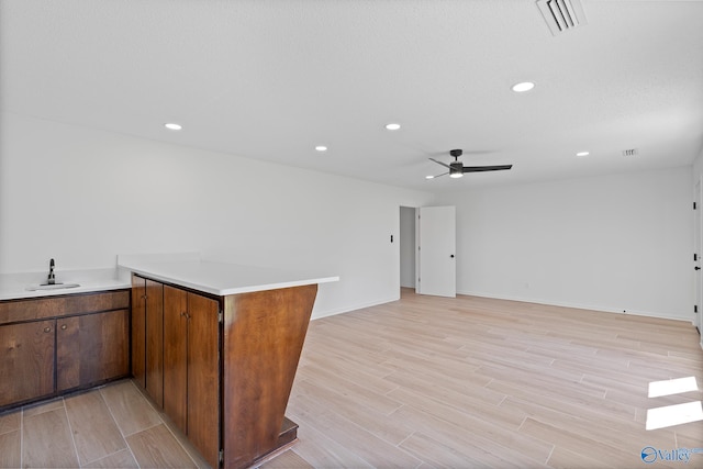 kitchen featuring visible vents, a peninsula, light wood-style flooring, and light countertops