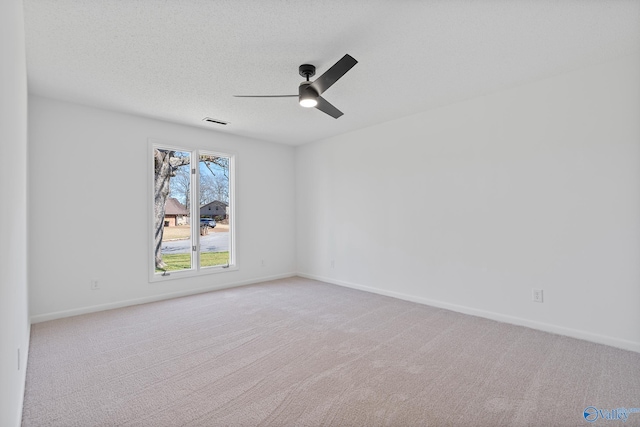 unfurnished room with carpet flooring, visible vents, a textured ceiling, and a ceiling fan