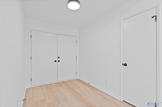 unfurnished bedroom featuring a closet, baseboards, and light wood-style floors