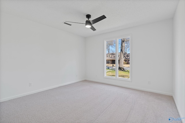 spare room with visible vents, light carpet, a ceiling fan, a textured ceiling, and baseboards