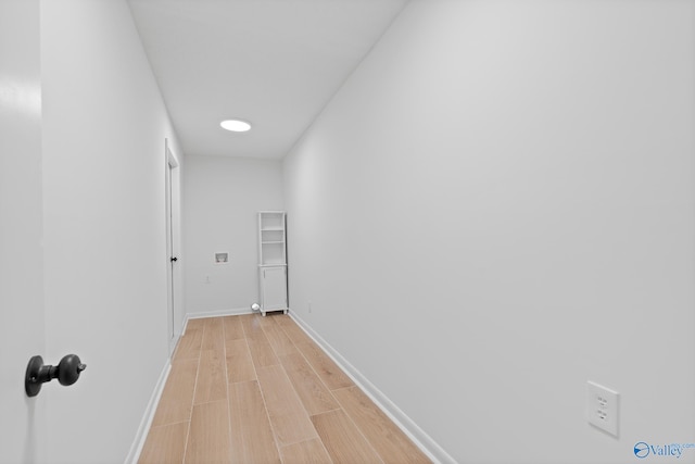 corridor with light wood-style floors and baseboards