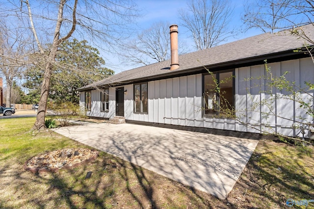 back of property featuring a lawn, entry steps, board and batten siding, roof with shingles, and a patio area