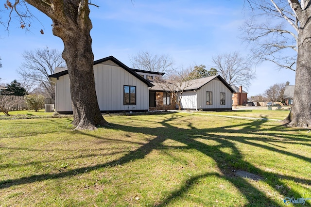 rear view of house featuring a lawn and board and batten siding