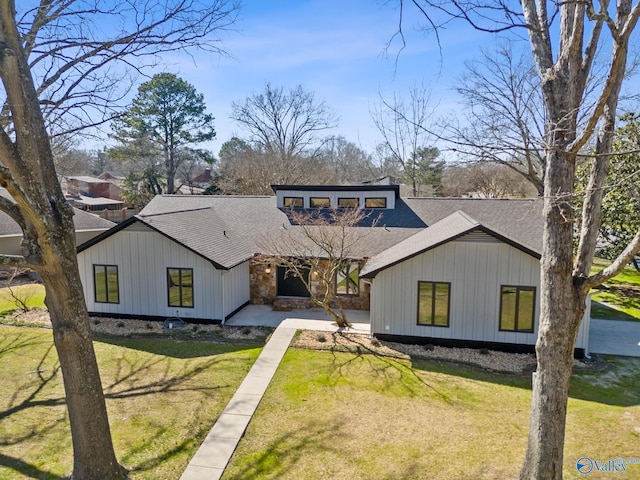 view of front facade featuring a shingled roof and a front yard