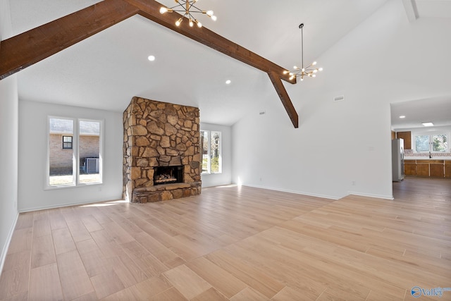 unfurnished living room featuring beam ceiling, plenty of natural light, light wood-style flooring, and an inviting chandelier