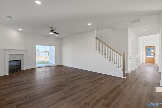 unfurnished living room with crown molding, dark hardwood / wood-style flooring, ceiling fan, and a premium fireplace