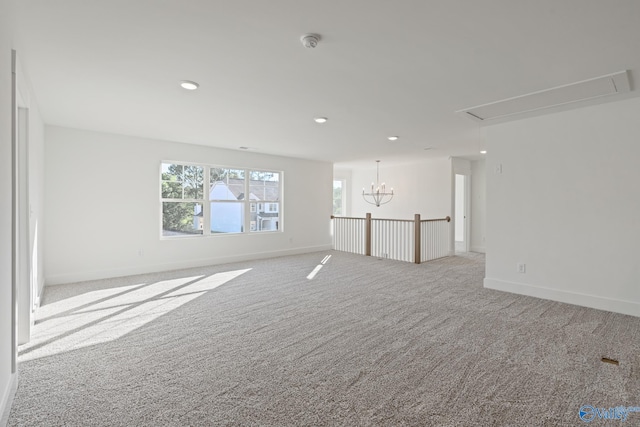 empty room with light colored carpet and a notable chandelier