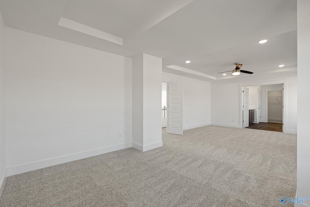 unfurnished living room featuring a tray ceiling, ceiling fan, and carpet floors