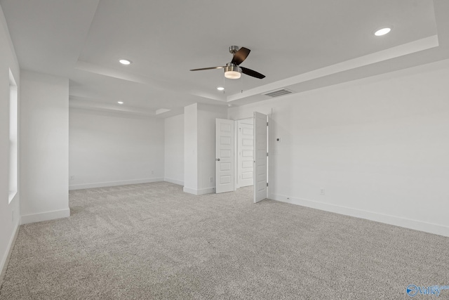 unfurnished bedroom featuring a raised ceiling, light carpet, and ceiling fan