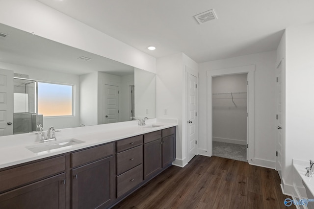 bathroom with wood-type flooring, vanity, and shower with separate bathtub