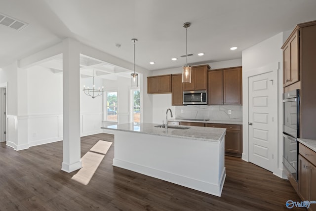 kitchen featuring backsplash, dark hardwood / wood-style flooring, stainless steel appliances, a kitchen island with sink, and sink