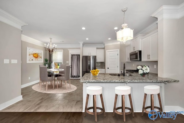 kitchen featuring stone counters, stainless steel appliances, white cabinetry, sink, and pendant lighting