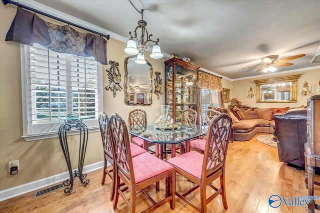 dining space with ornamental molding, wood-type flooring, and ceiling fan with notable chandelier