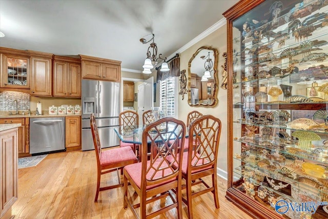 kitchen featuring crown molding, stainless steel appliances, an inviting chandelier, and light wood-type flooring