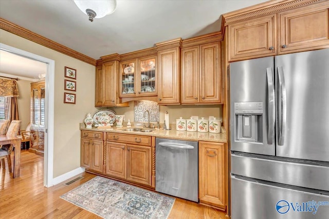 kitchen featuring sink, crown molding, appliances with stainless steel finishes, and light hardwood / wood-style flooring