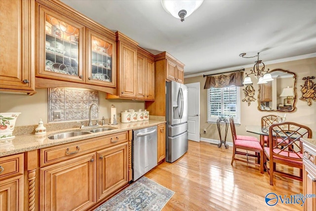 kitchen with hanging light fixtures, sink, crown molding, appliances with stainless steel finishes, and light hardwood / wood-style floors