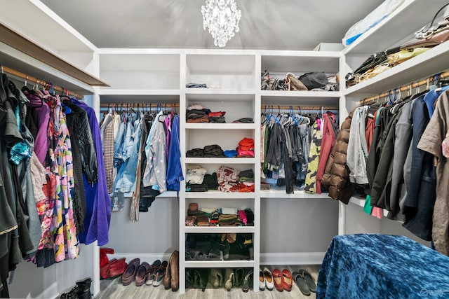 spacious closet featuring hardwood / wood-style floors and a chandelier