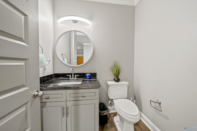 bathroom featuring hardwood / wood-style flooring, vanity, toilet, and crown molding