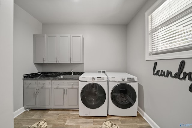 washroom with separate washer and dryer, sink, cabinets, and light hardwood / wood-style flooring