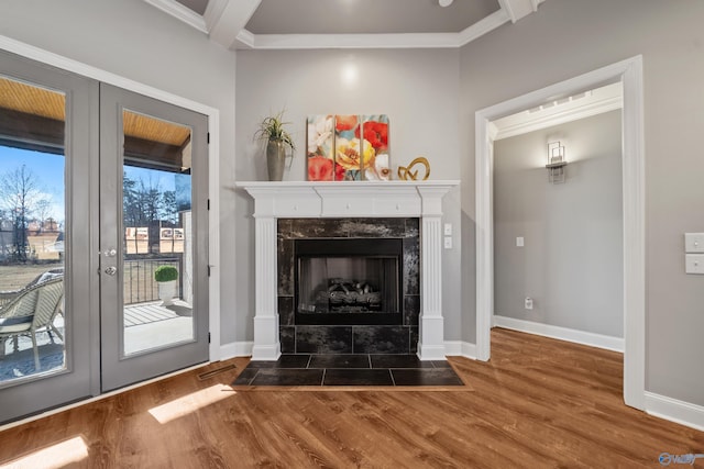 unfurnished living room with french doors, crown molding, hardwood / wood-style flooring, a premium fireplace, and beam ceiling