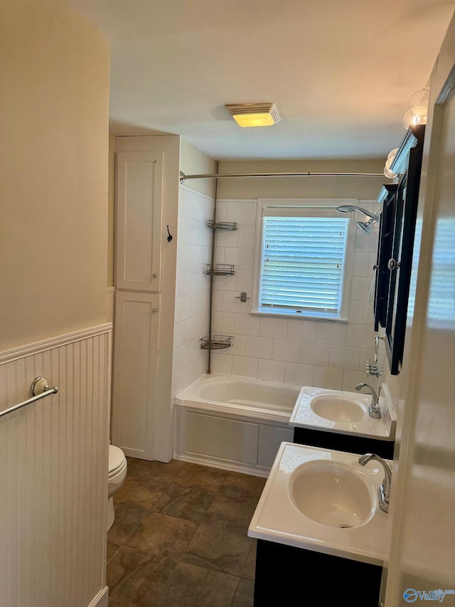 full bathroom with tile patterned floors, dual bowl vanity, tiled shower / bath combo, and toilet