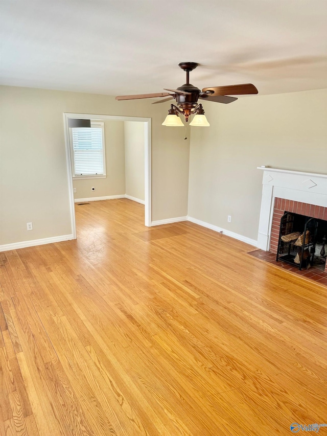 unfurnished living room with ceiling fan, light hardwood / wood-style floors, and a brick fireplace