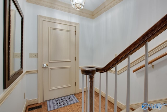 entrance foyer with visible vents, ornamental molding, wood finished floors, baseboards, and stairs