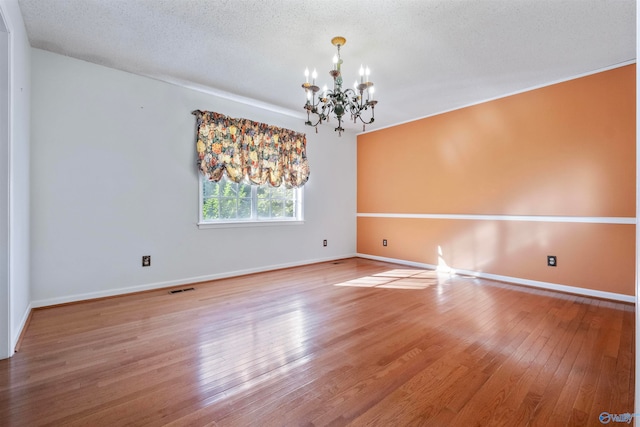 spare room featuring hardwood / wood-style flooring, a textured ceiling, and a chandelier