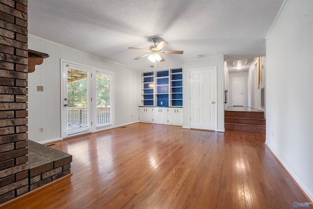 unfurnished living room with ceiling fan, wood-type flooring, a textured ceiling, and ornamental molding