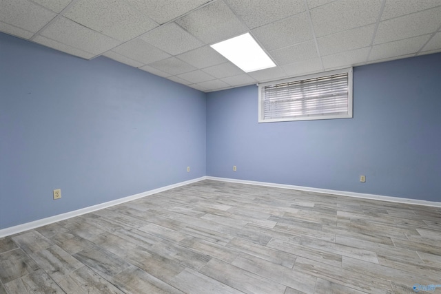 basement with a paneled ceiling and light hardwood / wood-style floors