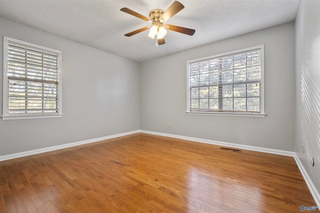 spare room with a wealth of natural light, a textured ceiling, and hardwood / wood-style flooring