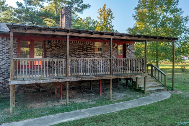 back of property featuring a deck and a lawn