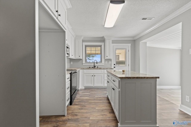 kitchen with white cabinetry, a center island, electric range, and hardwood / wood-style flooring