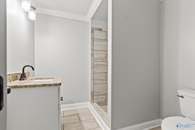 bathroom with a textured ceiling, vanity, toilet, and ornamental molding