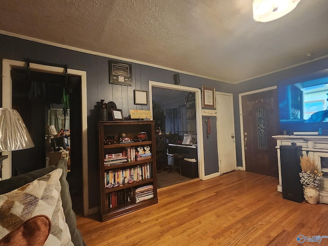 interior space featuring a textured ceiling, wood finished floors, and ornamental molding